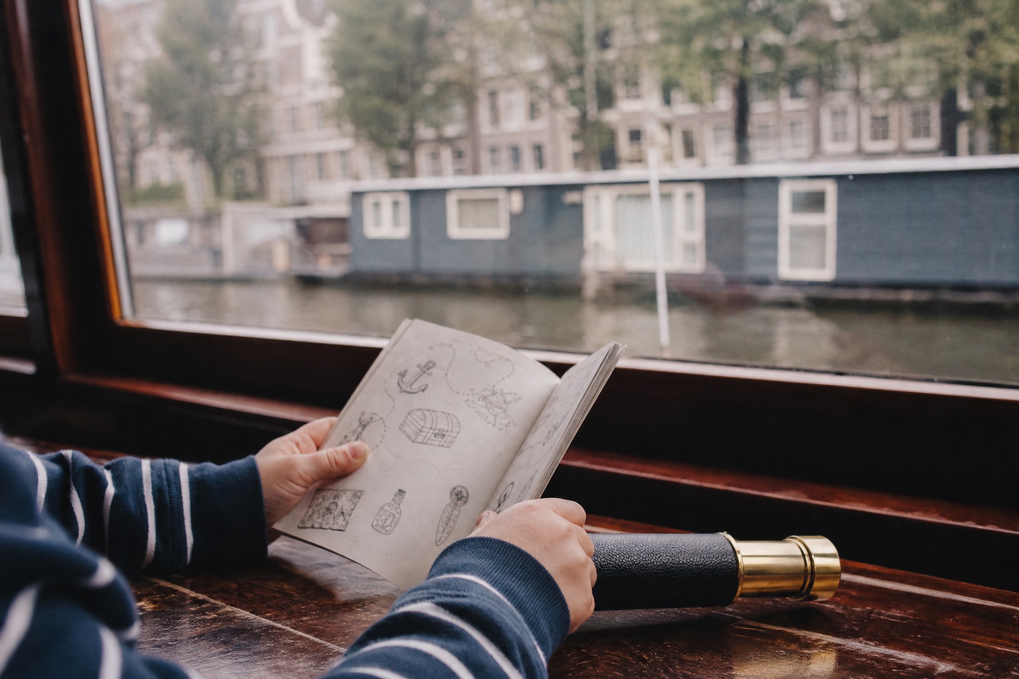 Child holding a pirate activity booklet and spyglass on an Amsterdam kids canal cruise