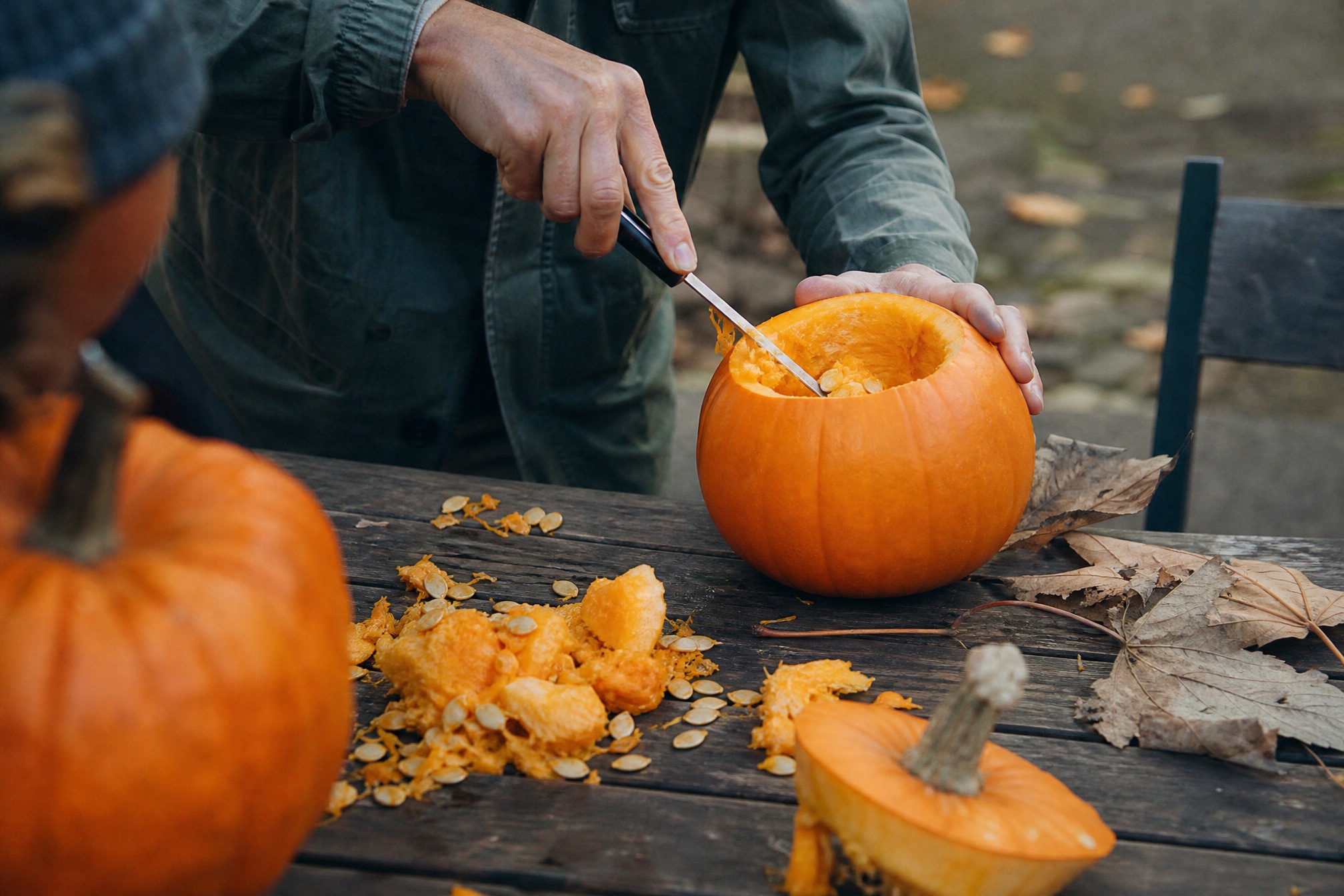 Hands carving a pumpkin outdoors, pumpkin carving for halloween with kids in the netherlands