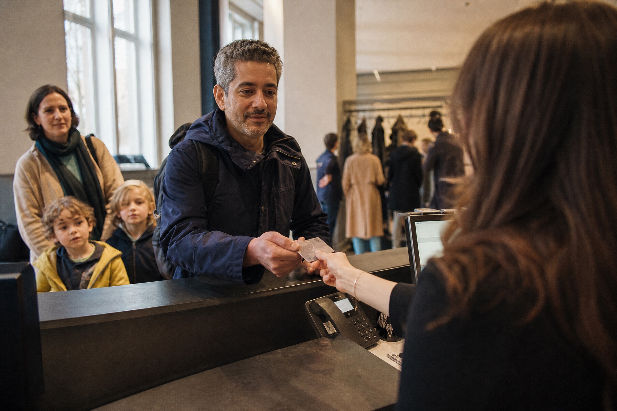 Family handing over a Museumkaart at a museum reception desk in Amsterdam