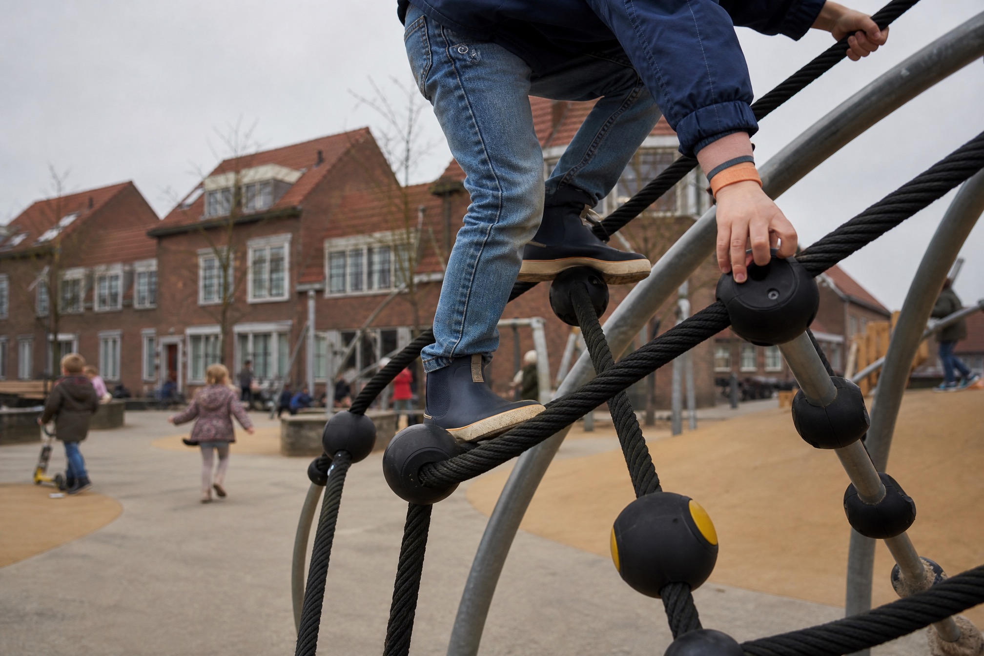 Child climbing a free public playground structure in a Dutch neighbourhood