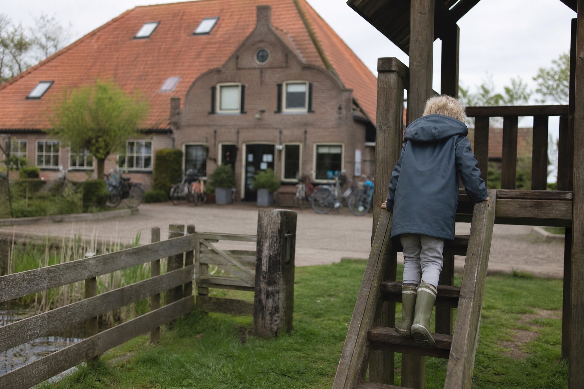 Child in a raincoat climbing a farm playground at a Dutch pancake farm restaurant