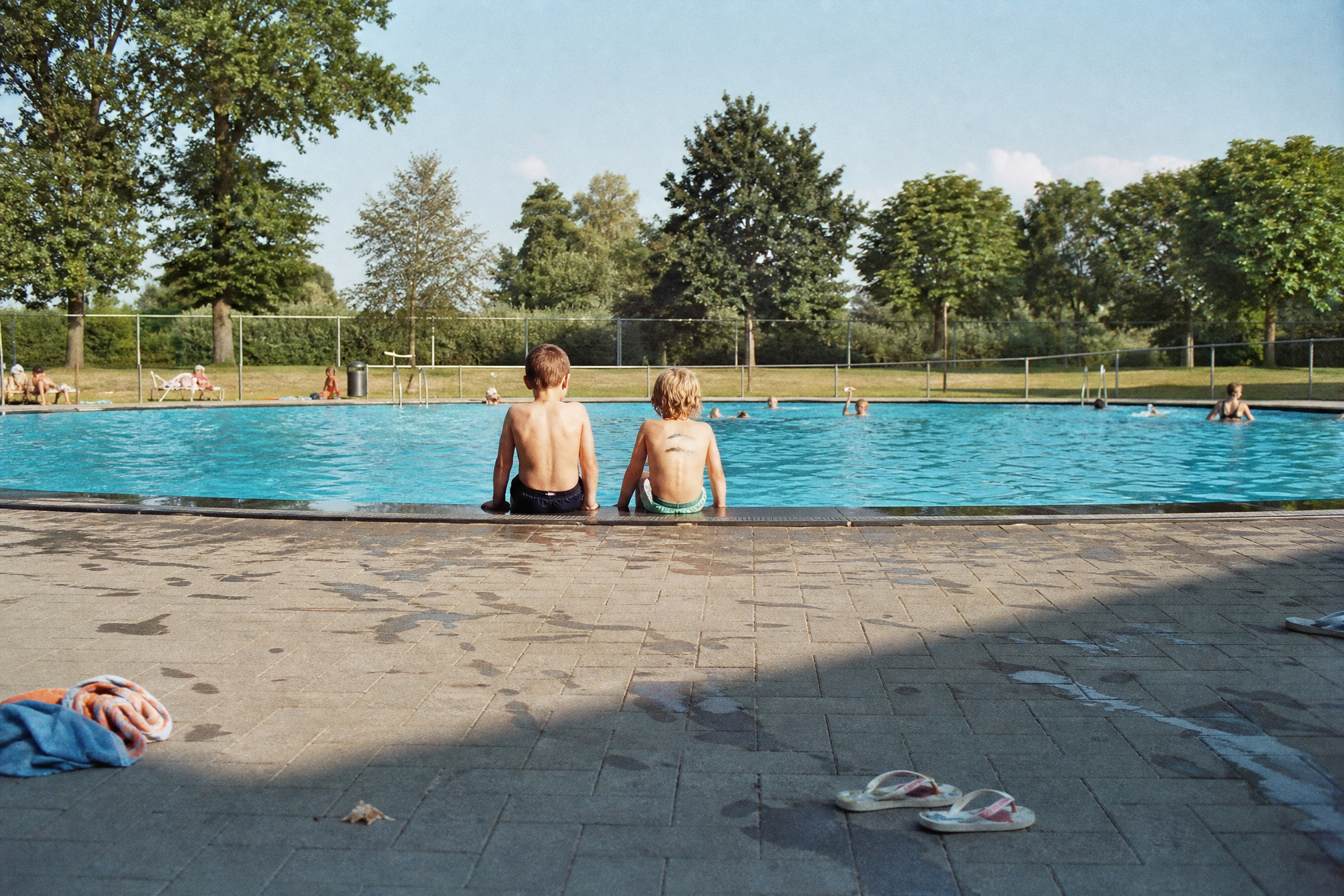 Kids sitting on the edge of an outdoor swimming pool in the Netherlands during a birthday party