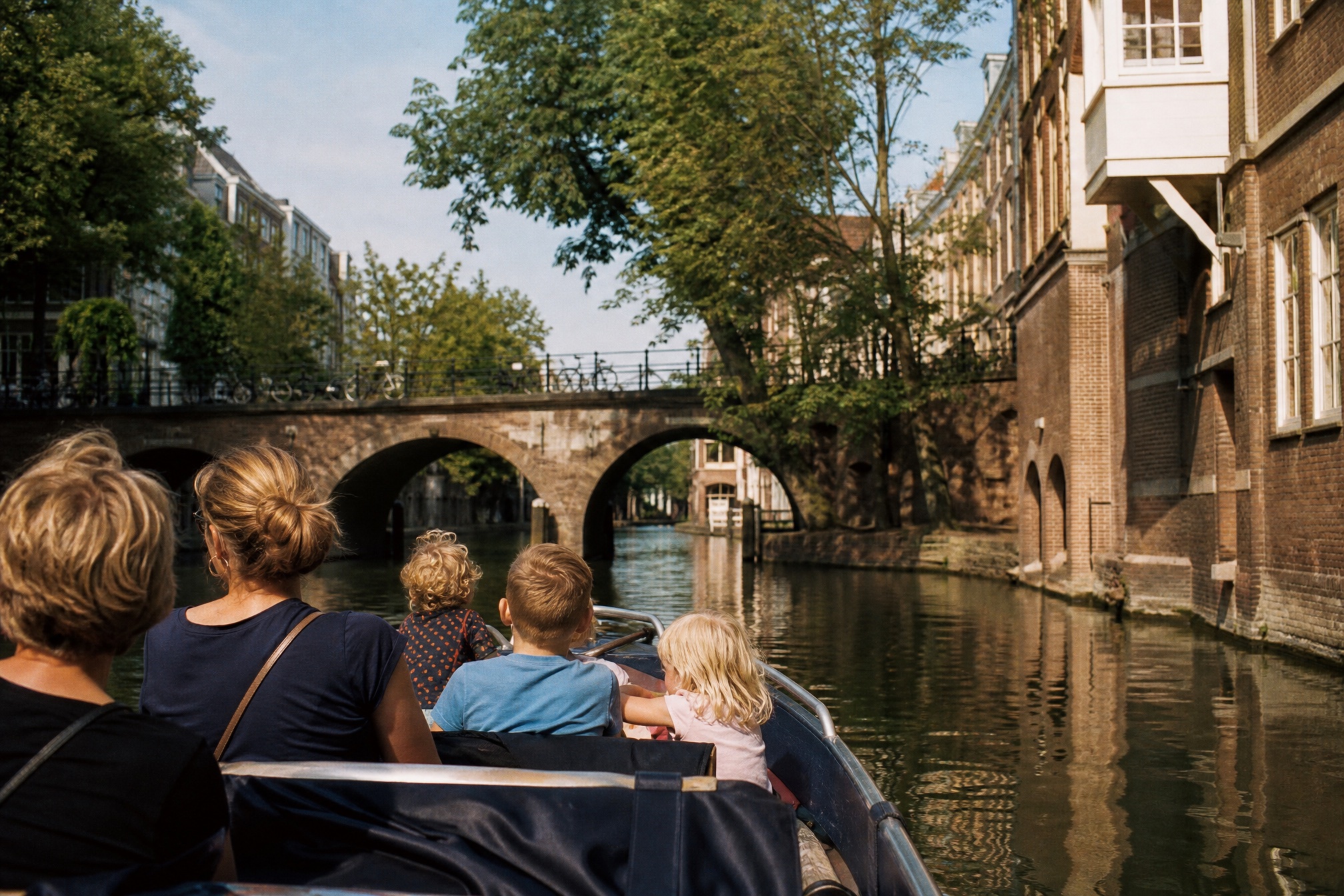 Family on a canal boat cruise passing under a bridge in Utrecht