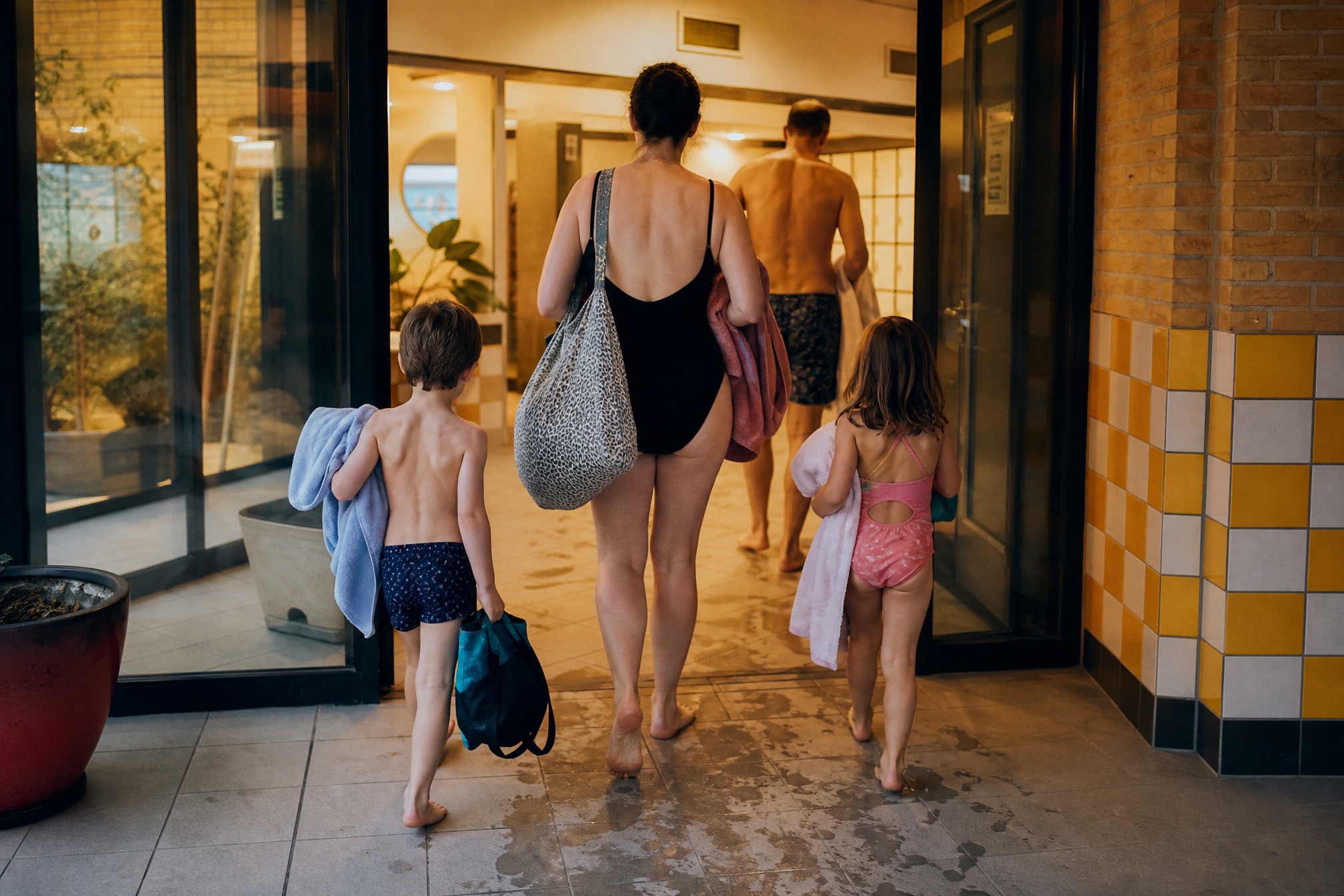 Family arriving at a Dutch swimming pool with towels and swim bags