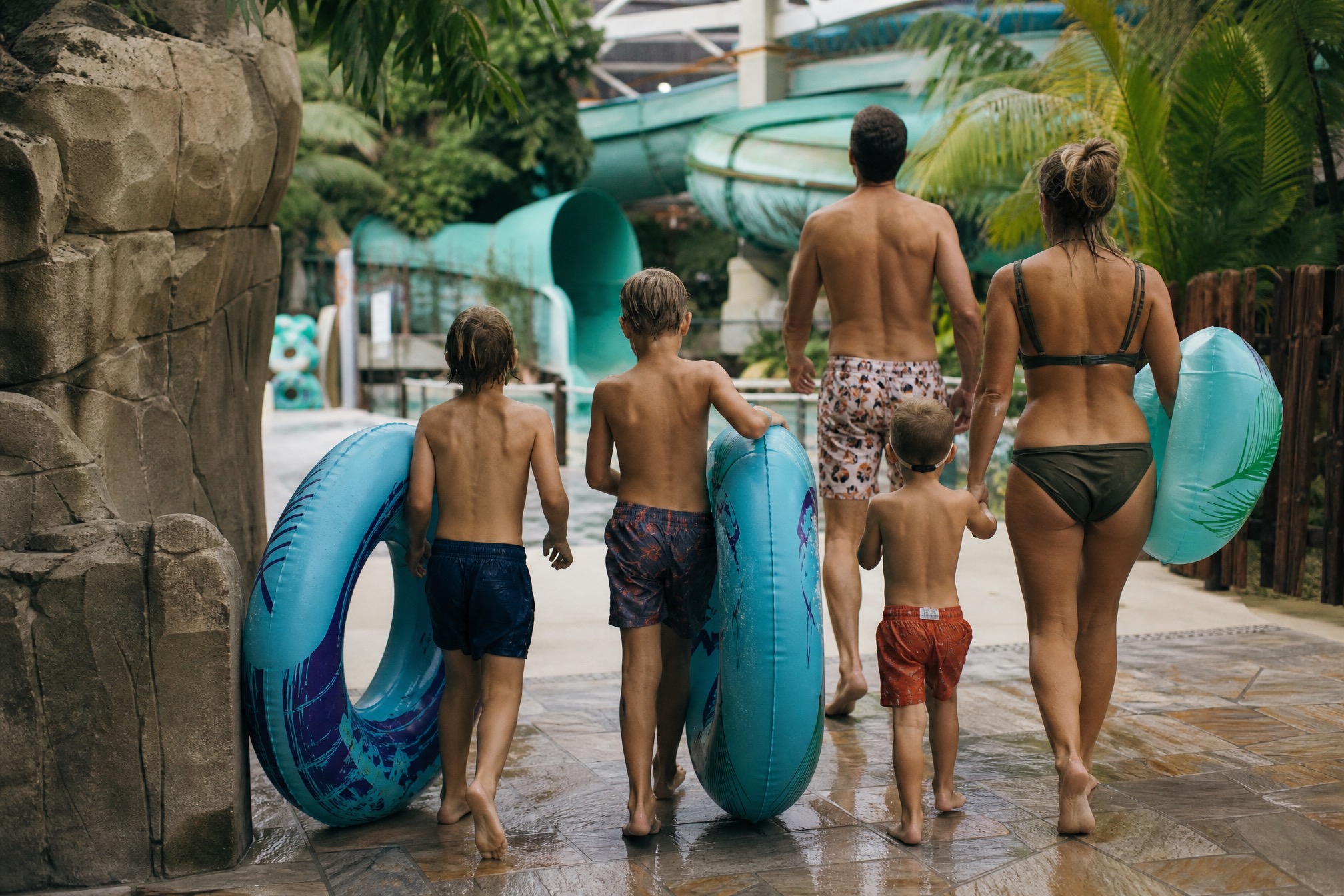 Family carrying pool floats toward water park slides in the Netherlands