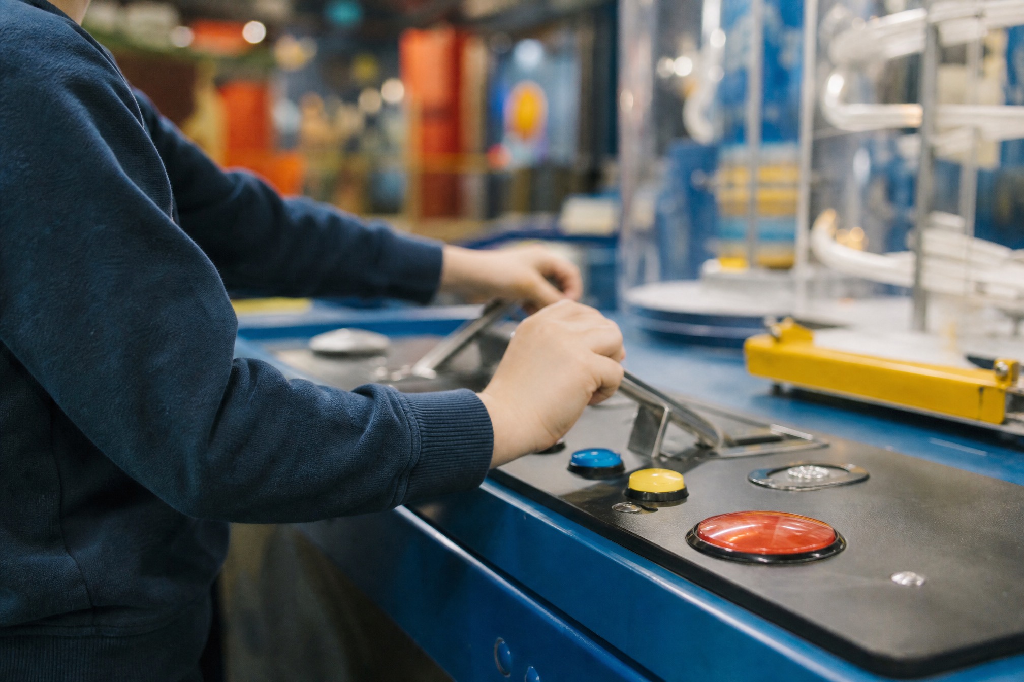 Child's hands operating buttons and levers at an interactive science museum exhibit in the Netherlands