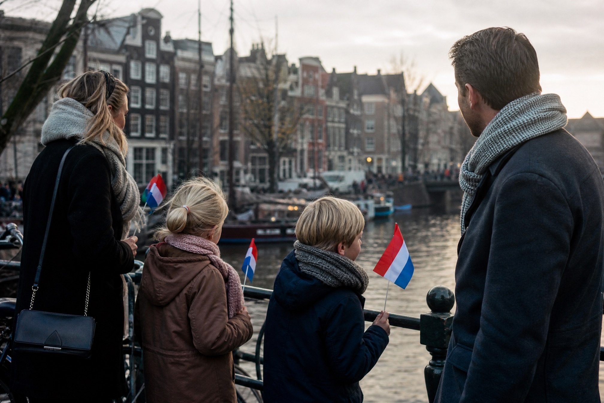 Family with young kids holding Dutch flags watching the Sinterklaas arrival parade