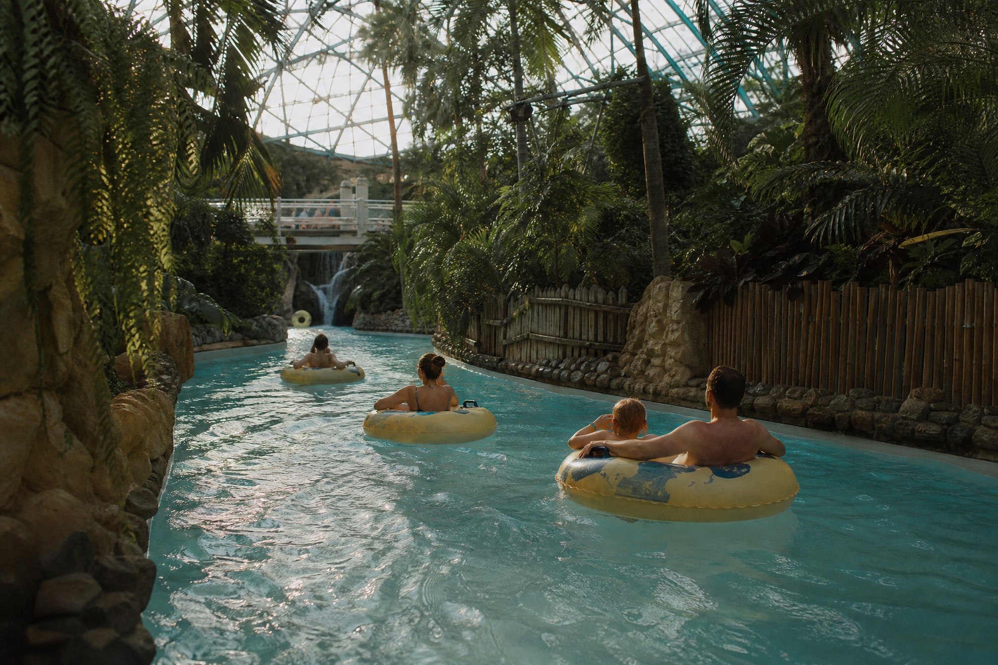 Family floating on rings down the lazy river at a subtropical swim paradise water park