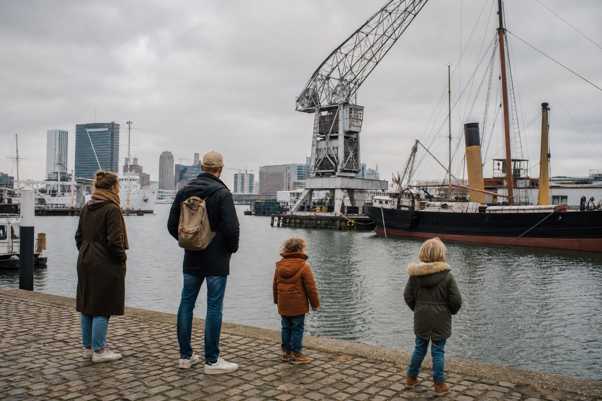 Family looking at historic ships and cranes in the Rotterdam museum harbour with kids