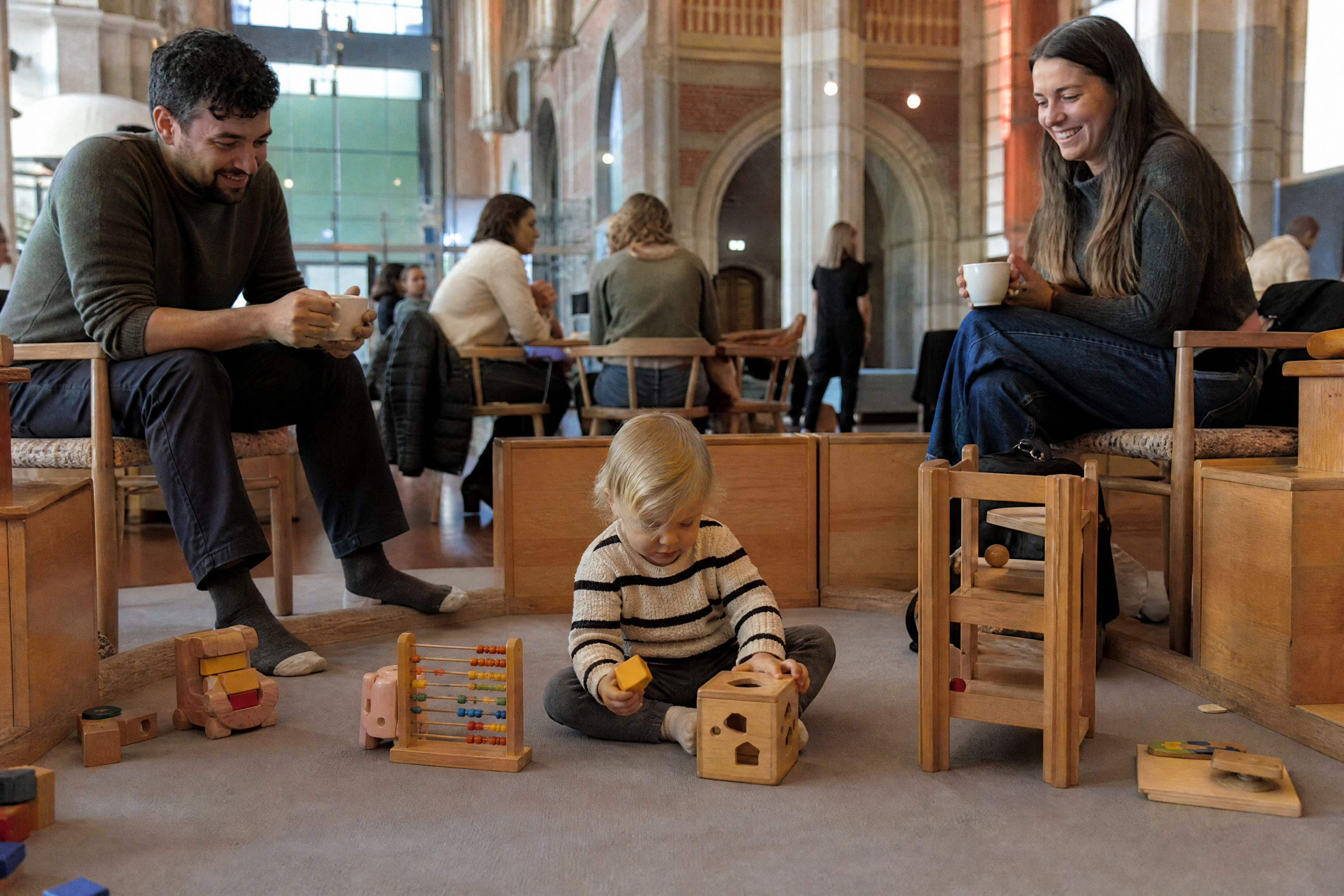 A toddler plays in a museum cafe play corner in Amsterdam while parents have coffee nearby