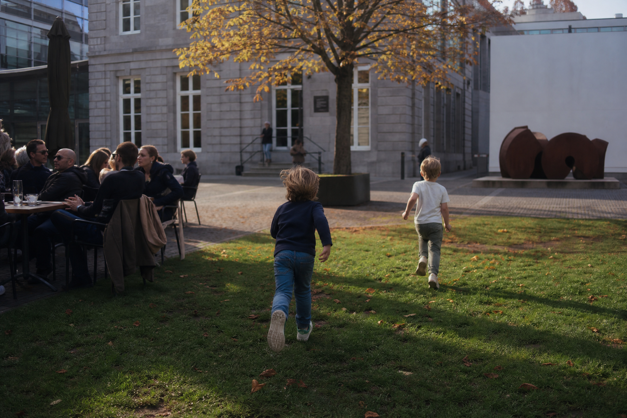 Kids running on the grass outside a museum cafe terrace in the Netherlands