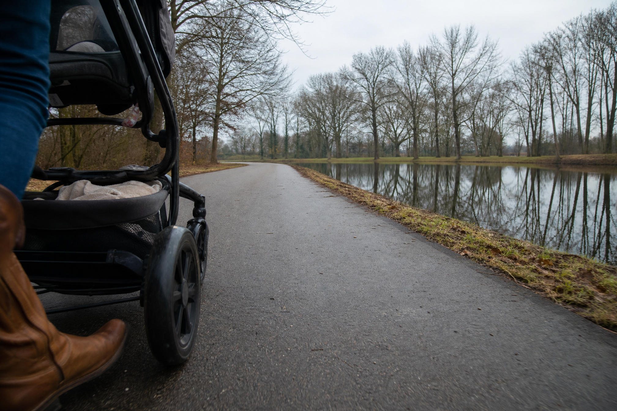 Stroller wheels on a paved winter walking path next to a lake in an Amsterdam park